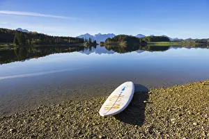 A calm lake with a surfboard on the shore