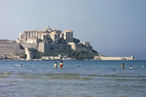 Calvi, Korsika, Frankreich in den spaeten 1950er Jahren Menschen beim Schwimmen mit der Zitadelle der Stadt im Hintergrund