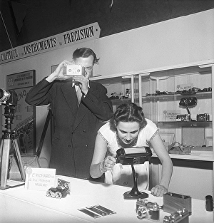 Camera history. A man with a Jules Richard Paris Verascope holds it up at a trade fair
