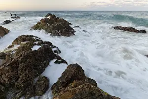 The Cape Byron Lookout at high tide: rocks and anglers in golden light