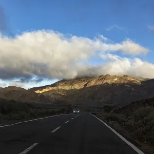 Car driving on road TF-24 through volcanic landscape