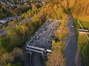 Empty car park surrounded by dense trees and a road in the evening light