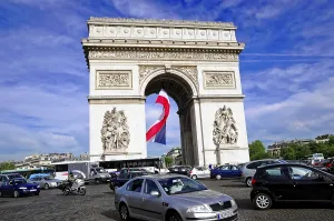 Car traffic around the Arc de Triomphe with blue sky in the background