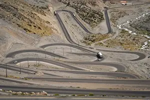 Cars trucks and lorries driving on the twisting and turning switchback road through high Andes in Chile