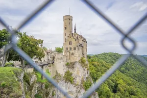 Castle on a hill, framed by green forest and viewed through a lattice