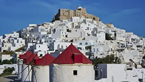 Castle and windmills above white houses under a sunny sky