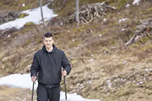 Casual and active healthy man hiking in Alpine mountains with trekking poles