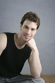 Casual young man portrait sit over gray grunge background