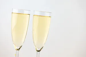 Two champagne glasses against a bright background
