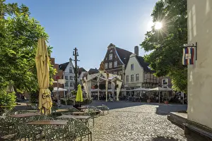 Category Cities DE Prints: Charming square with half-timbered houses and parasols under a bright blue sky