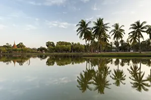 Chedi with palm trees and reflection in water