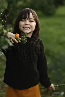 Cheerful child in a cozy sweater enjoys a moment in a vibrant green orchard