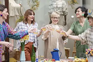A cheerful group of women raise their glasses in a toast