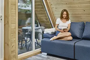 Cheerful woman sits comfortably on a sofa in tiny house