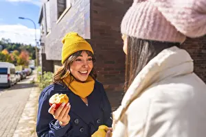 Two cheerful women friends enjoying fresh apples