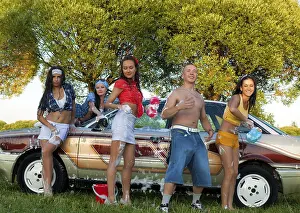 Cheerful young female friends in casual clothes standing near vintage car and looking at camera