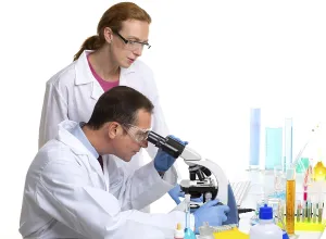 Chemical laboratory with two scientist working with test tubes and microscope