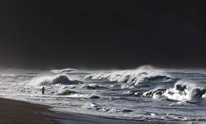 Child bathing on the sandy beach of Praia de Santa Barbara in stormy sea with high waves