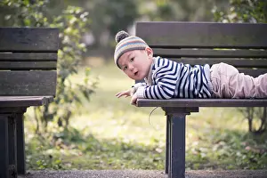 Framed Print : Child lying on a bench in the park