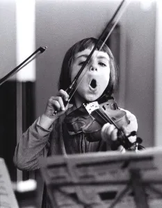 Child plays violin and sings, England