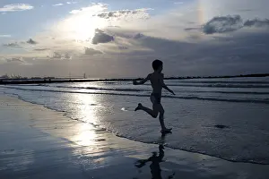 Child walks into the sea, backlit, Germany