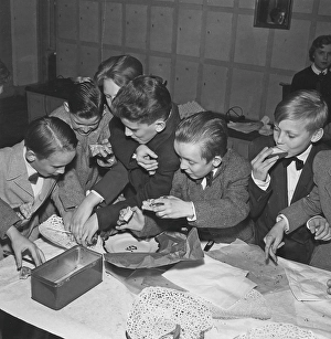 Children in the 1950s. A group of boys at a party are grabbing and fighting over the cookies and buns