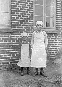 Children of a baker family pose with aprons and headgear for the photo