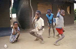 Children in front of a clay hut on the side of the road