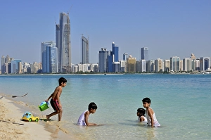 Children playing in water, Abu Dhabi skyline in the back