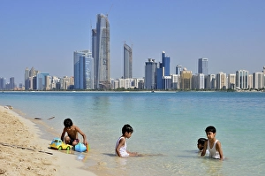 Children playing in water, Abu Dhabi skyline in the back