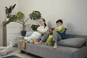 Two children sit on a gray couch