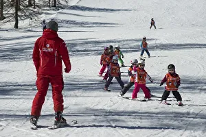 Children ski lessons with instructor on the piste