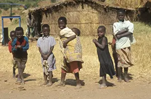 Children in front of a straw hut on the side of the road