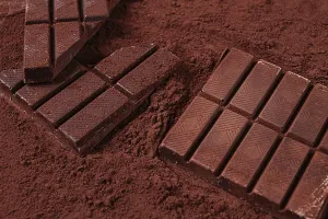 Chocolate bars broken and scattered on cocoa powder background with rich texture and color