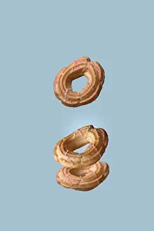 Choux pastry donuts flying on a blue background