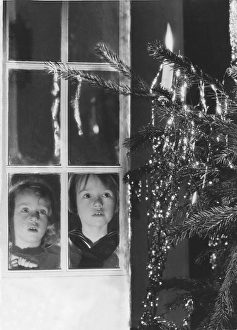 Christmas in the 1940s. Two children are looking at the christmas tree at christmas eve