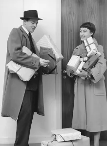 Christmas in the 1950s. A couple with christmas gifts after a shopping tour returning to their home and struggles a bit with the key to the door. 1953