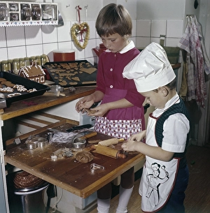 Christmas in the 1950s. A girl and a boy is busy in the kitchen baking ginger bread