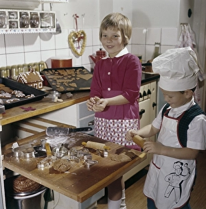 Christmas in the 1950s. A girl and a boy is busy in the kitchen baking ginger bread