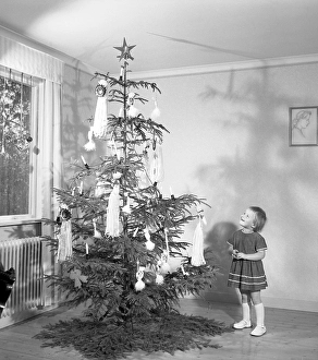 Christmas in the 1950s. A young girl is standing by the christmas tree
