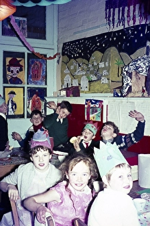 Christmas party time in primary school classroom children wearing hats and eating pulling funny faces, UK, c 1960
