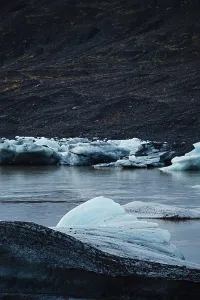 Chunks of blue ice floating in water with dark