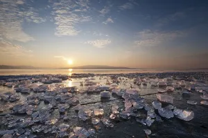 Chunks of ice lying on icy surface on the shore of Reichenau Island at sunset