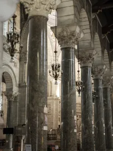 Church interior featuring tall ornate columns and hanging chandeliers in Tours