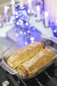 Two cinnamon rolls in a glass dish surrounded by candles and blue lights