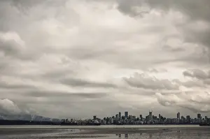 Framed Print : City skyline with towering buildings under a cloud-filled sky