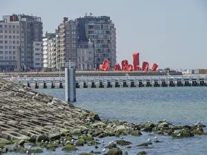 City view by the sea with modern buildings and red art figures on the pier