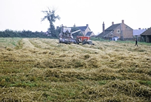 Claas combine harvester harvesting in a field with tractor and trailer, England, UK 1968