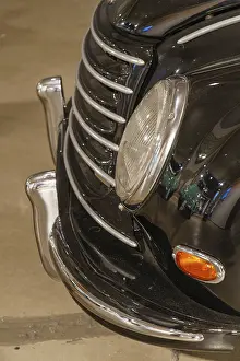 Front of a classic car with chrome details and striking headlights
