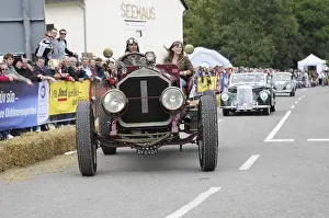 A classic car races in front of spectators on the street
